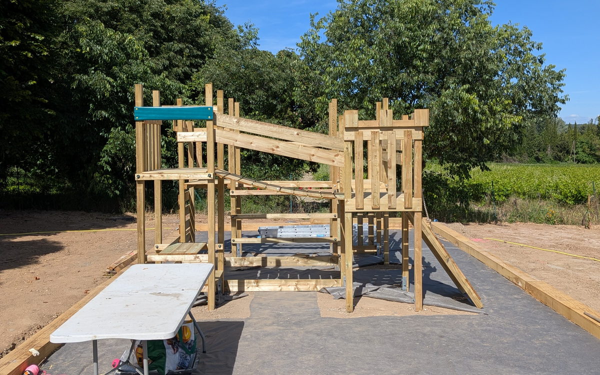 Structure de jeu en bois terminée : tour, passerelle et toboggan